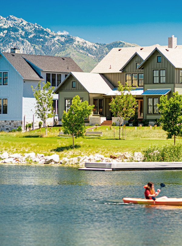 Communities-Sidebar-Pic A Rainey Home on the Island in Daybreak, UT with the snowy Wasatch Mountains in the background and a kayaker the Oquirrh Lake.